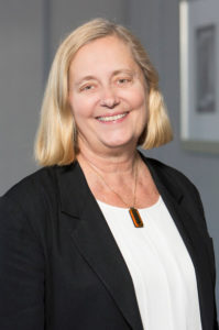 Picture of Cathy Ficker Terrill smiling with necklace. 